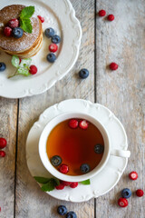 Delicate pancakes with fruits and berries on a wooden table.