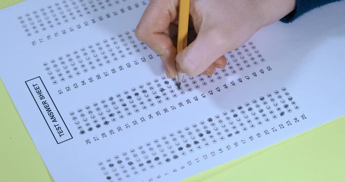 Filling out a standardized test answer sheet with a pencil for education and assessment purposes in a classroom or testing center setting