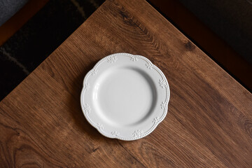 Ceramic white flat plate for food on wooden table top view	