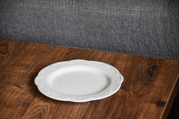 Ceramic white flat plate for food on wooden table top view	