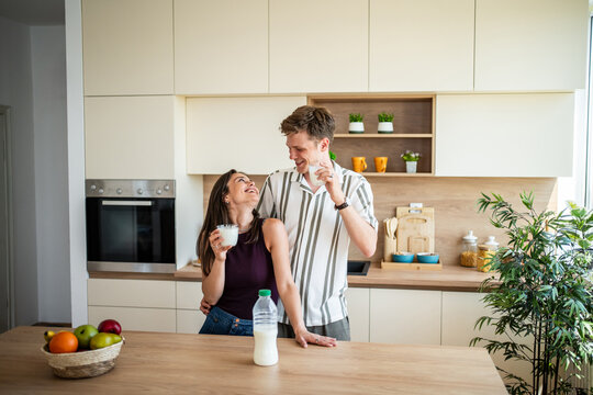 Young couple enjoying healthy breakfast and milk in kitchen - Powered by Adobe
