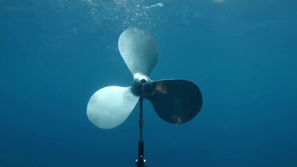 Close-up underwater shot of a boat propeller with three blades, suspended in the ocean. - Powered by Adobe