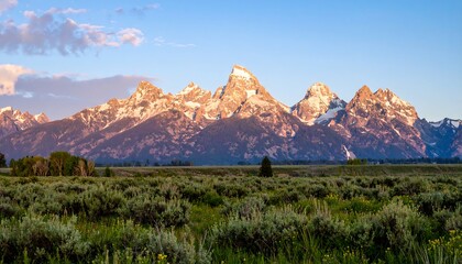 Fototapeta premium Mountain range at sunrise over a meadow