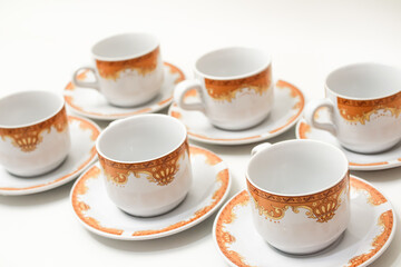 Elegant tea set featuring white cups with intricate golden and brown crown designs displayed on saucers