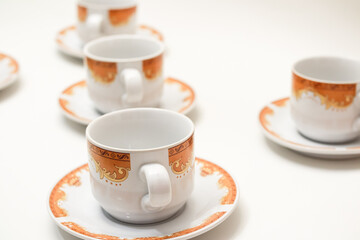 Elegant tea cups with intricate orange patterns on a clean white surface