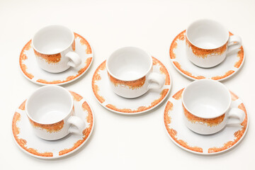 Elegant arrangement of white ceramic teacups with decorative orange designs on saucers