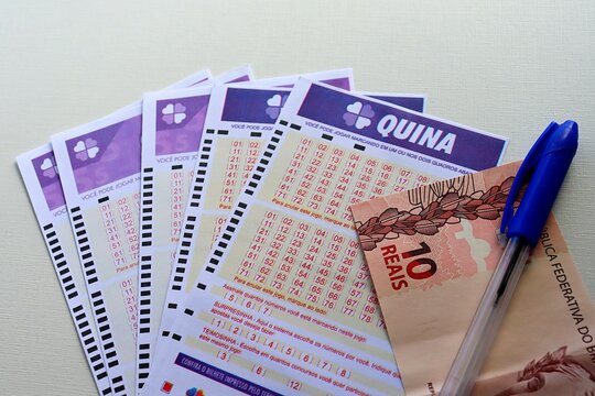 Salvador, Brazil - October 4th, 2025: Quina game and Brazilian Real banknote. Quina Brazilian Lottery (Loterias Caixa) concept. Millionaire prize.