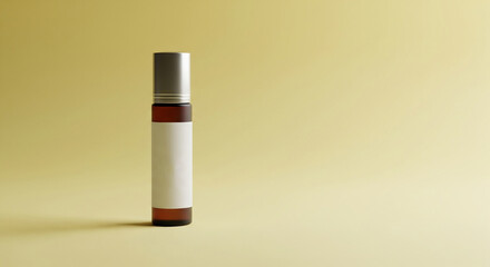 Minimalist amber roller bottle with blank label and silver cap on soft yellow background
