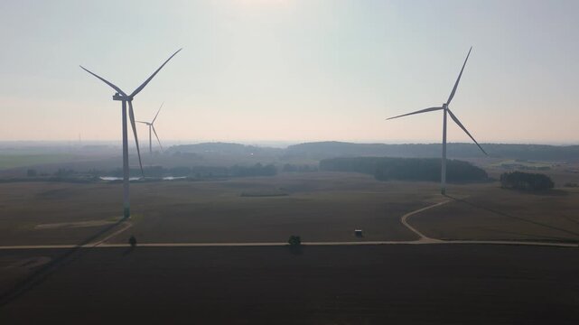 Wind Turbines Generating Renewable Energy over Farmland at Sunrise in Countryside