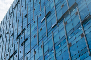 Close-up view of high-rise office building facade with reflection of blue sky