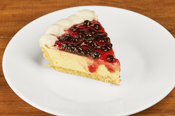 Cheesecake with elderberry jelly topping on a white background, close-up shot with copy space
