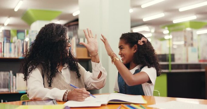 Book, teacher and high five with child for learning, support and development in school library. Girl, happy student and success with educator for education achievement, well done or talk for teaching - Powered by Adobe
