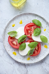 Plate with classic italian caprese salad on a white stone background, vertical shot, high angle view