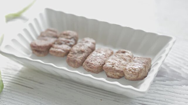 Close-Up of Romanian Mici Sausages Served with Flatbread and Tomatoes on a White Plate	
