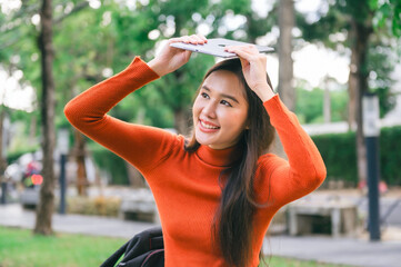 woman wearing an orange sweater is holding  tablet in her hand