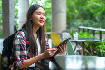 woman is sitting at  table with  tablet in her hand