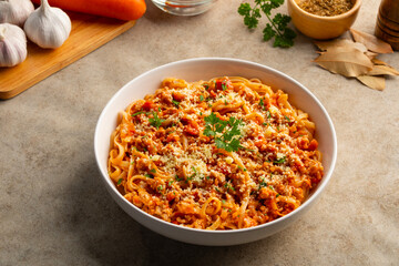 Fettuccine pasta with Ground meat and tomato,spaghetti with a meat based bolognese tomatoes,served on white plate with parmesan cheese.