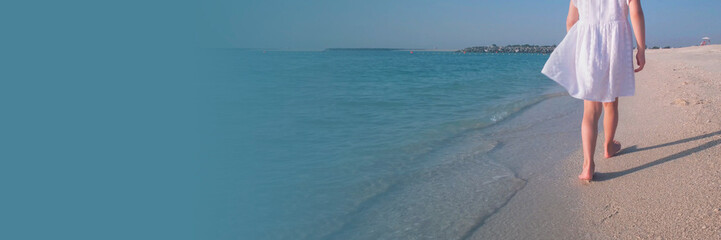 Young Girl Strolling on Serene Beach in White Dress