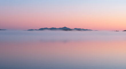 Fototapeta premium Tranquil Sunrise Landscape with Mountains Reflected in Misty Water
