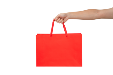 A person's hand holding a paper shopping bag with handles on a clean white background. Studio shot with ample copy space for text, logos, or branding. Isolated on white, cut out.