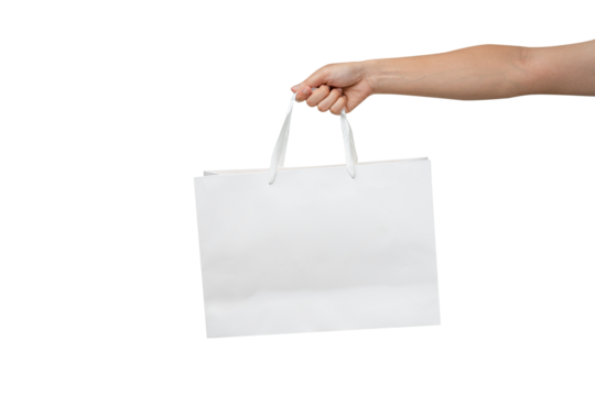 A person's hand holding a paper shopping bag with handles on a clean white background. Studio shot with ample copy space for text, logos, or branding. Isolated on white, cut out.