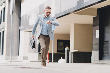 Businessman hurries along a modern city street in a stylish formal suit carrying a briefcase...