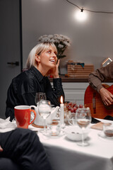 A joyful woman gazing warmly while sharing an evening of fun, dining, and acoustic music with friends in a cozy atmosphere.