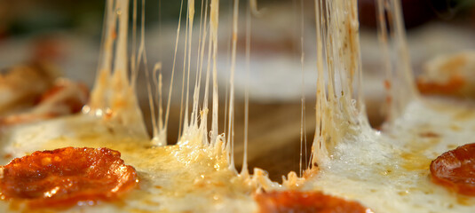 Warm pepperoni pizza offering a delicious close-up view of gooey, stretching melted mozzarella...