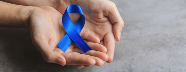The blue ribbon held gently in cupped hands symbolizing awareness and support
