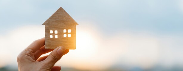 The House Cutout Held In Hand At Sunset Symbolizing Homeownership And Investment
