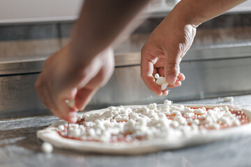 Chef pizzamaker preparing pizza with cheese topping in pizzeria kitchen