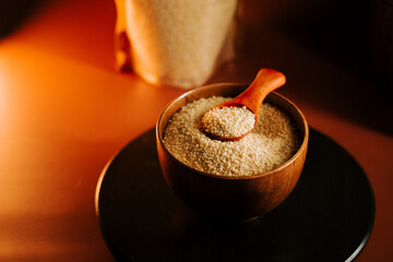 Uncooked couscous in a wooden bowl with a spoon on a wooden surface