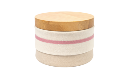 A cylindrical wooden and fabric storage box.  A light beige/cream colored fabric layer sits below a pale, pinkish-red fabric band, held within a light brown wooden lid