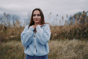 Natural portrait of a woman wearing a soft blue knit cardigan outdoors, conveying authenticity and...