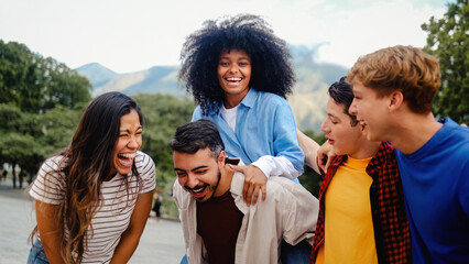 Young diverse friends having fun hanging out in public park. Friendship and multiracial concept. Vertical photo