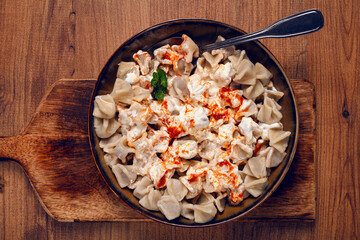 Traditional Turkish dumplings served with yogurt and spicy sauce on a green decorative plate