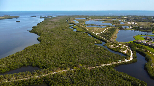Aerial view of Robinson Preserve and its trails in Bradenton, FL, featuring Perico Bayou and Tampa Bay surrounding lush trails. Blue waters and green landscapes under a clear sky.