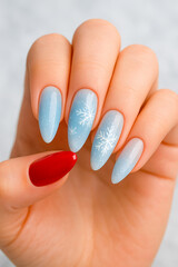 Close-up of a hand showcasing a frosty blue gradient manicure with delicate white snowflake accents. Perfect for winter fashion, seasonal beauty, and holiday nail trends.