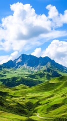 Obraz premium Lush Green Hills and Majestic Mountains Under a Bright Blue Sky with White Clouds