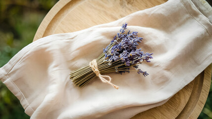 A delicate bundle of lavender binds with twine rests on a softly lit linen cloth atop a wooden tray, evoking rustic, calm, and natural home decor vibes.