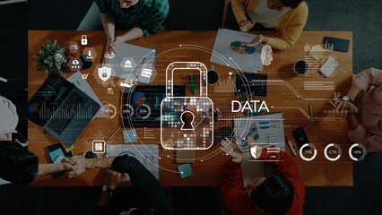 Aerial view of a dynamic office setting where team members collaborate on data security and digital strategies. Modern tools and visuals emphasize innovation and teamwork. Raster