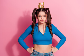 Obraz premium Young woman with a crown and playful ponytails posing confidently in stylish fashion on a vibrant pink background