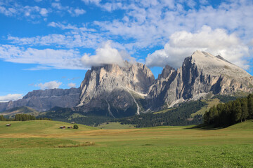 White clouds crown Sassolungo as meadows stretch in quiet harmony below