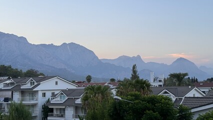Hazy peaks of the Taurus Mountains at sunset, overlooking white residential apartment buildings and...