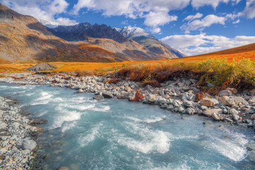 Russia. Altai Mountains. A mountain river against the backdrop of an autumn valley.