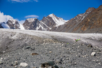 Russia. Altai Mountains. Udachny Glacial Pass. Small figures of tourists with backpacks.