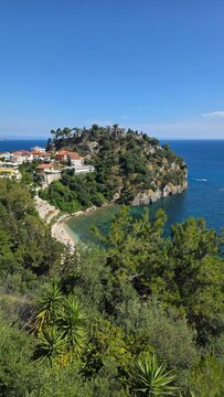 Panoramic view of Parga Greece with Venetian castle ruins, Ionian Sea coastline, lush greenery and traditional houses. Perfect travel destination photo with beach and blue sky.