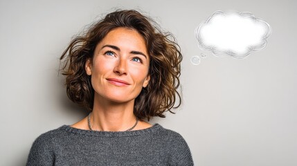A woman with short brown hair and a gray sweater is looking up at a white cloud. The cloud is shaped like a thought bubble, which suggests that the woman is thinking deeply about something