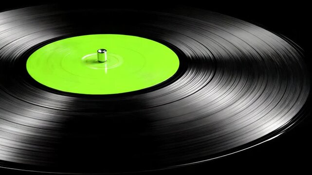 A close-up of a vinyl record with a vibrant green label and a silver spindle