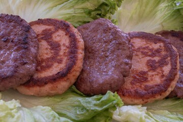 Grilled beef and chicken patties on lettuce leaves, homemade burger concept